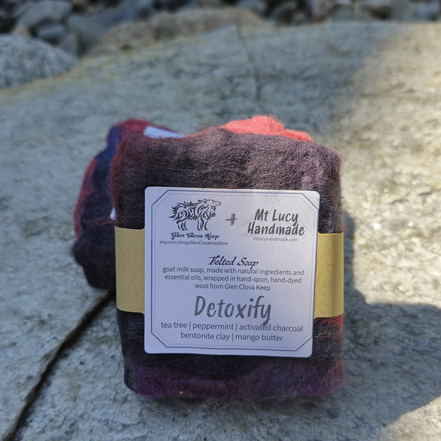 detoxify square soap wrapped in dark purple felt and white label on a slate background