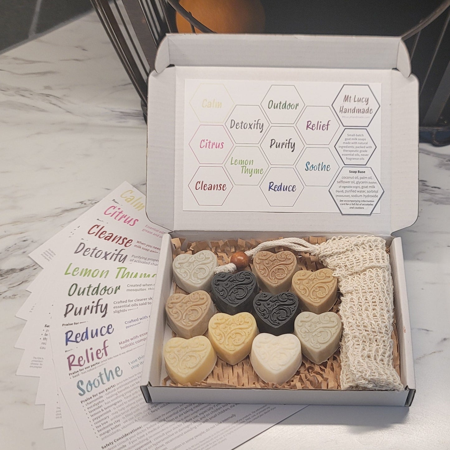 box of 10 heart shaped soaps with a sisal soap saver bag, sitting on a counter with information cards fanned out underneath 