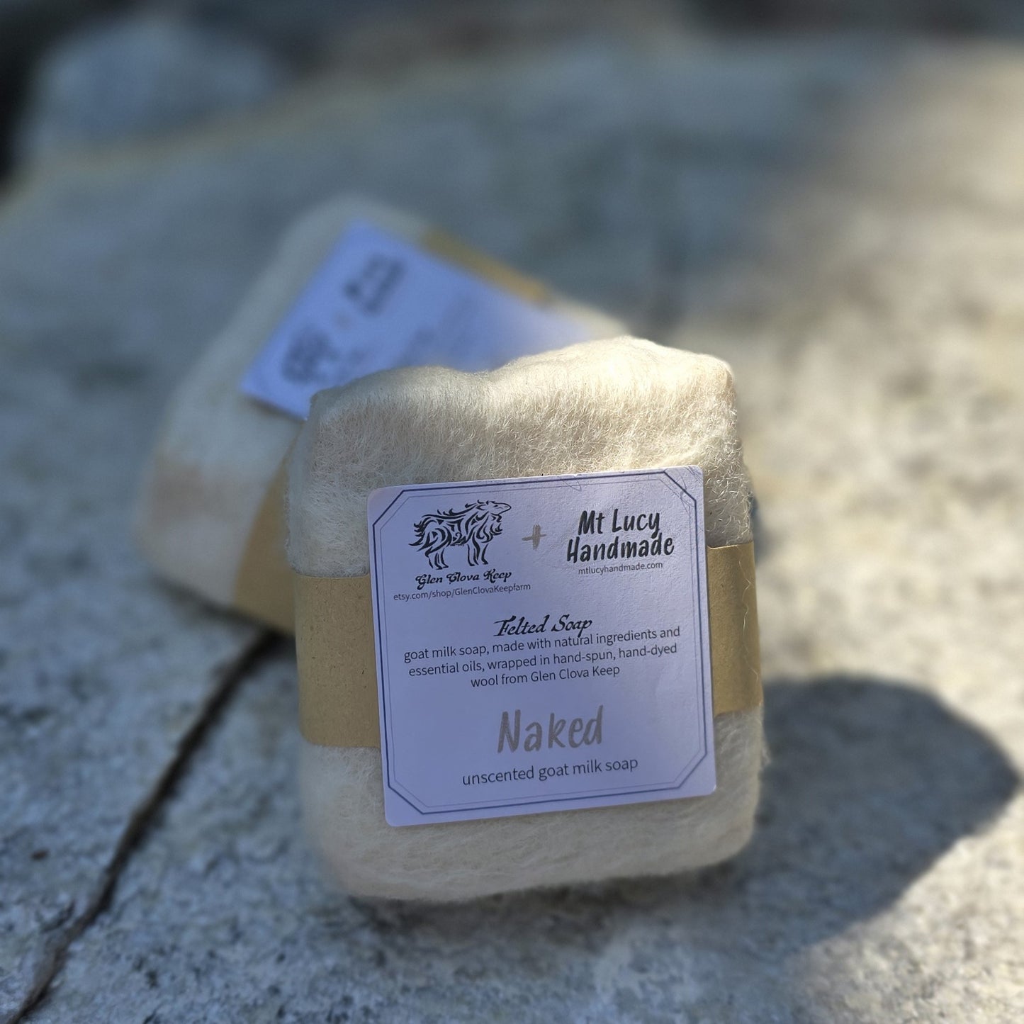 naked square soap with cream colored felt and white label on a slate background