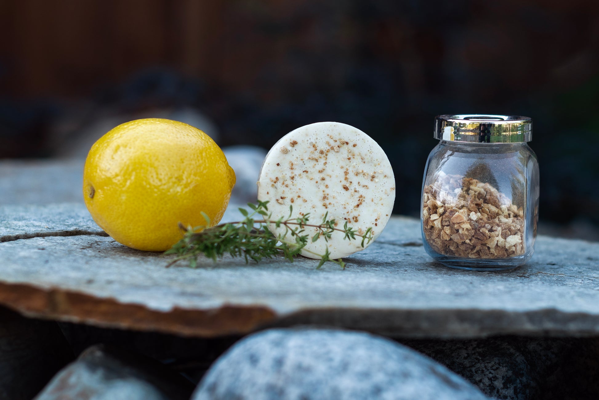 our lemon thyme soap, topped with ground lemon peel, surrounded by a lemon, fresh thyme and a jar of ground lemon peel